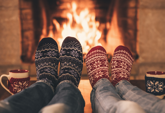 Disability and Dating: two people's feet in cozy socks in front of a warm fire, a festive environment