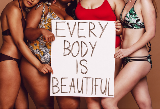 Four women of diverse ages, races, and sizes holding a sign that reads "every body is beautiful"