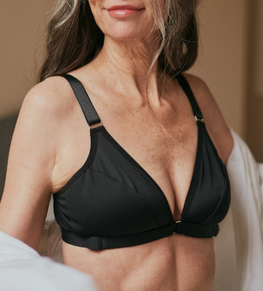 Attractive, mature woman with a half smile wearing the Springrose velcro adaptive bra and a white button down