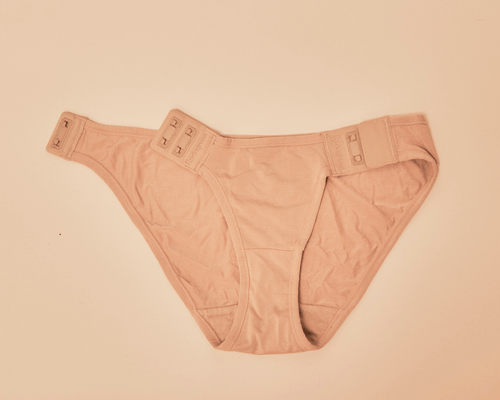 The Springrose adaptive underwear in beige laying flat with one of the magnet closures open.