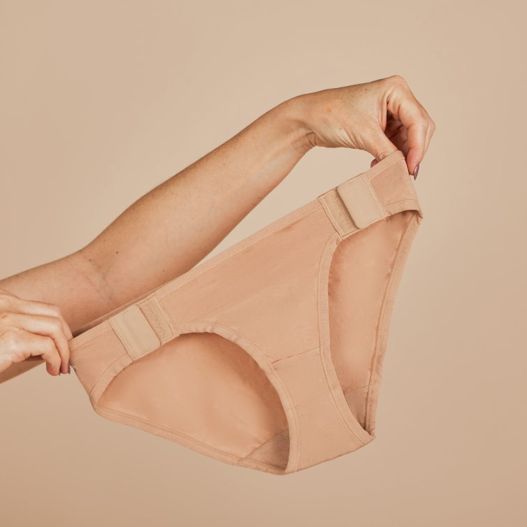 Image of someone holding up Springrose's adaptive underwear with magnetic side closures in beige.
