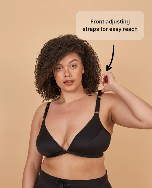 A beautiful young woman wearing the Springrose adaptive bra while pulling on the wide shoulder straps, with the text reading "front adjusting straps for easy reach"