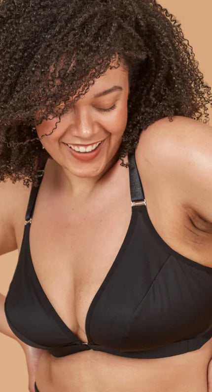 Young beautiful woman smiling while looking down and shrugging her shoulders in the adaptive one arm bra