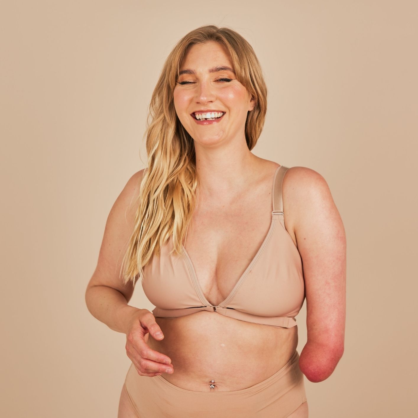 Beautiful model with a limb difference laughing while wearing the Springrose Velcro adaptive bra in beige