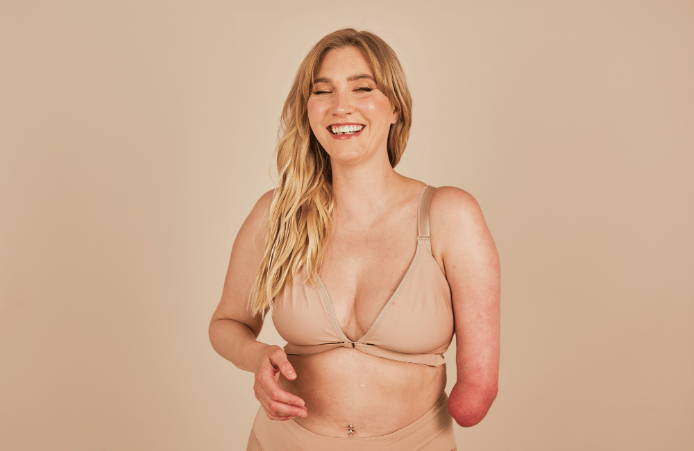 Beautiful model laughing with a limb difference showcasing the Springrose adaptive one handed bra in beige