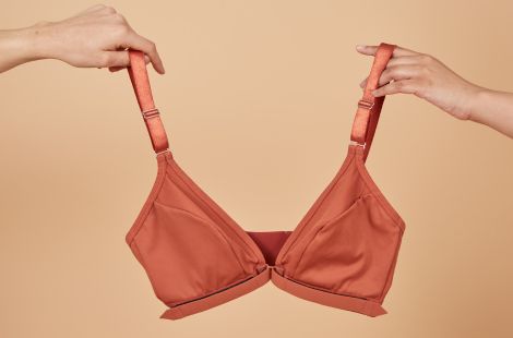 Two hands holding up the adaptive fibromyalgia bra in terracotta