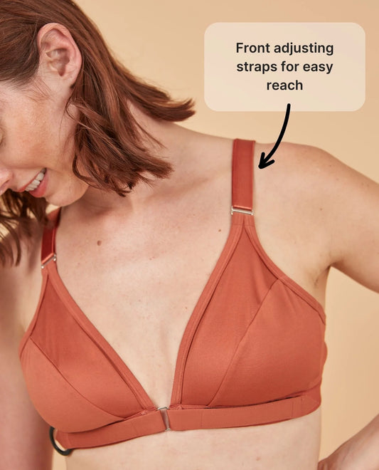 The Springrose adaptive bra on a beautiful woman who's smiling, but most of her face is out of sight. The text points at the wide shoulder straps and reads: front adjusting straps for easy reach