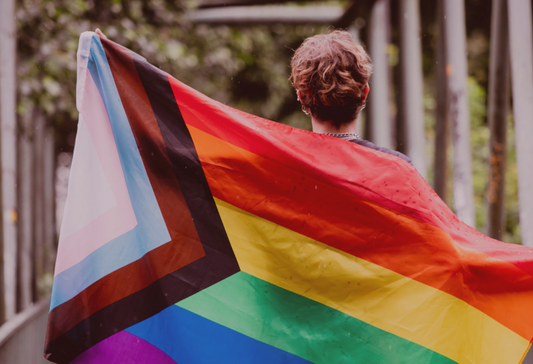 Woman holding up the pride flag behind her