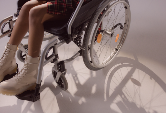 Close up of a person in a wheelchair, with only the legs and wheelchair visible
