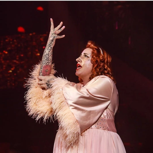 White, red-headed woman in a pink robe, performing a burlesque routine about stroke