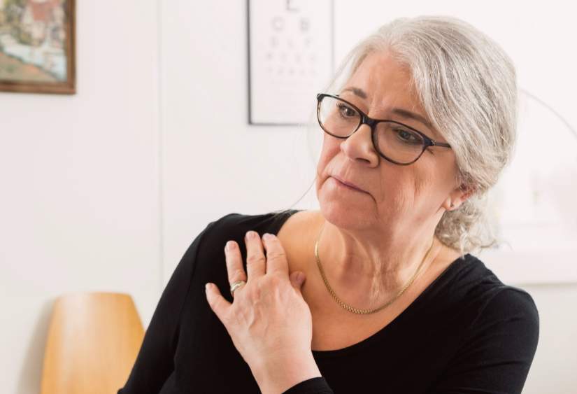 Can You Wear a Bra After Rotator Cuff Surgery? A mature woman touches her shoulder and looks concerned.