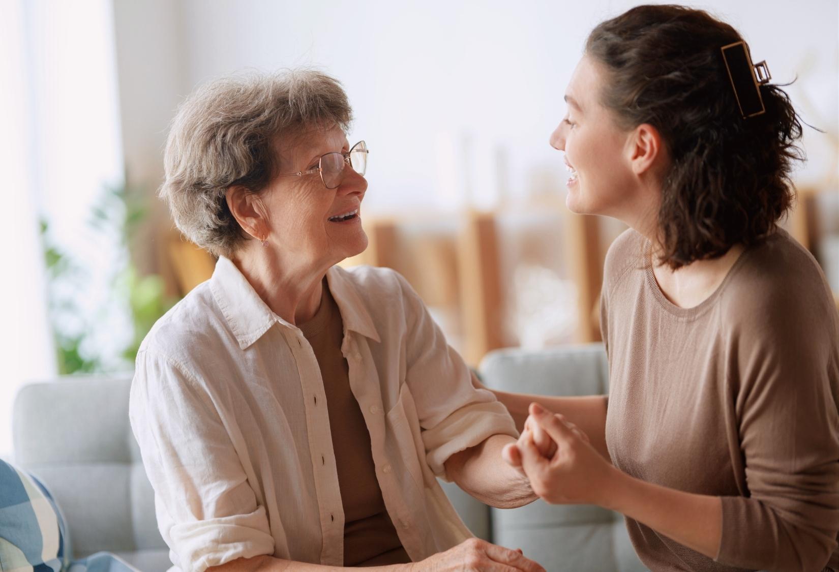 Caregiving for a Family Member at Home 101: Caregiver holding hands with smiling senior family member at home