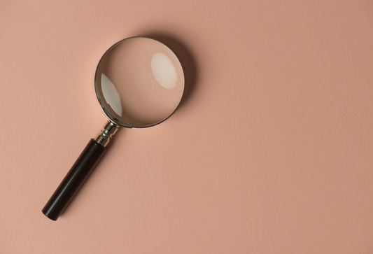 Finding the Right Pelvic Floor Therapist For and Near You: image of a magnifying glass on a light brown background
