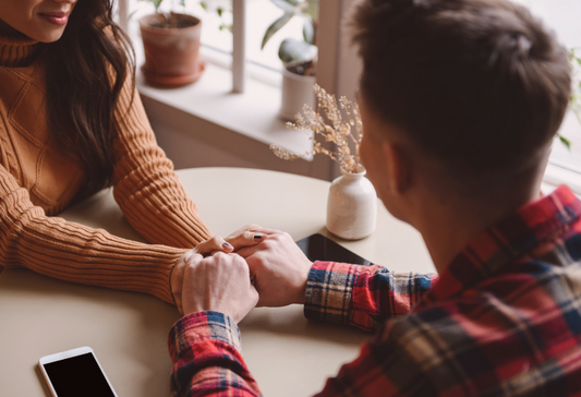 Disability and dating: a woman and a man holding hands across a table while on a romantic date
