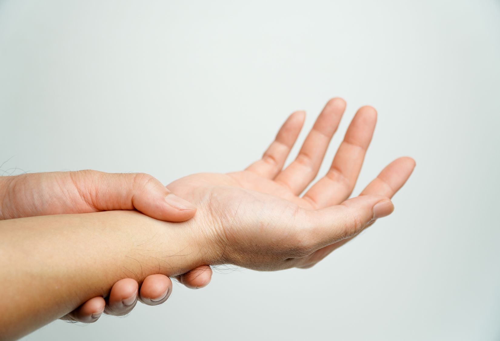 EDS Compression Clothing: A woman holding their wrist gently, indicating pain or discomfort in her wrist.