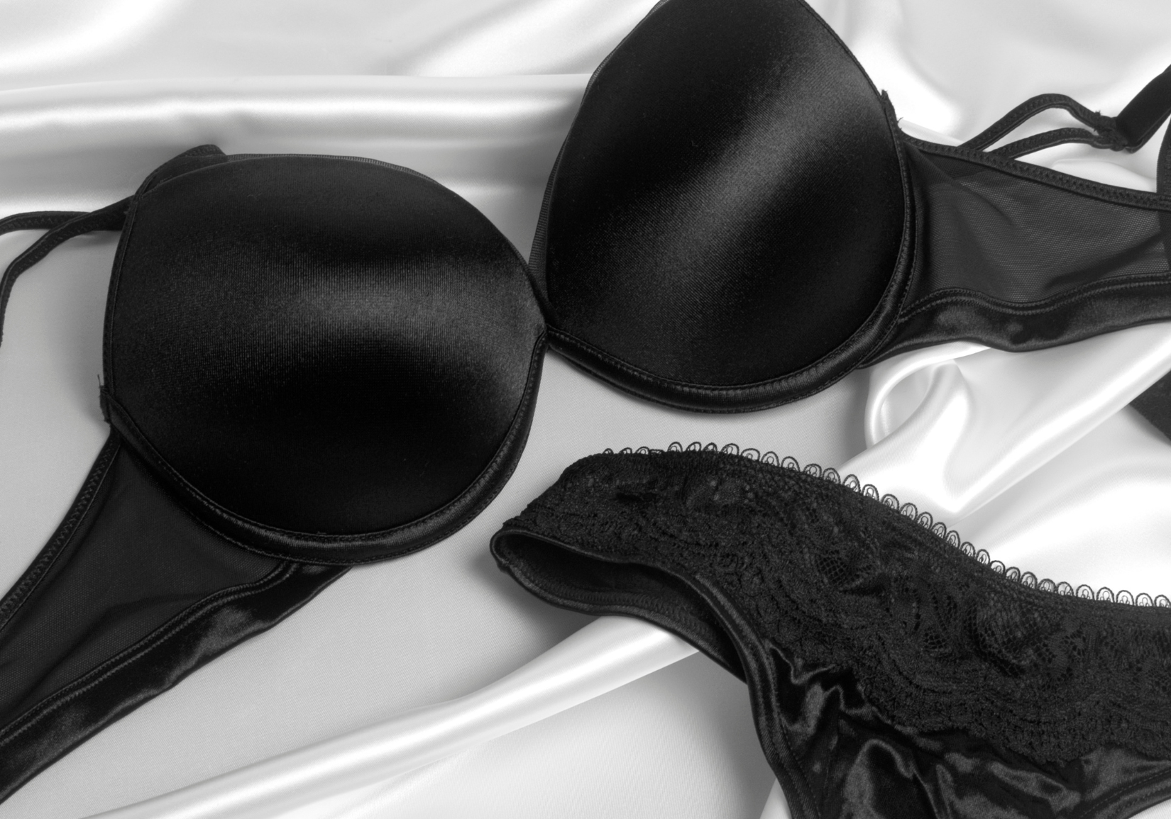 How often should I replace my bras: black bra and underwear on satin white sheets