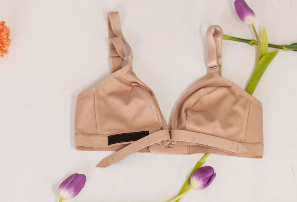 How find bra size: an adaptive velcro bra laying flat with flowers around it 