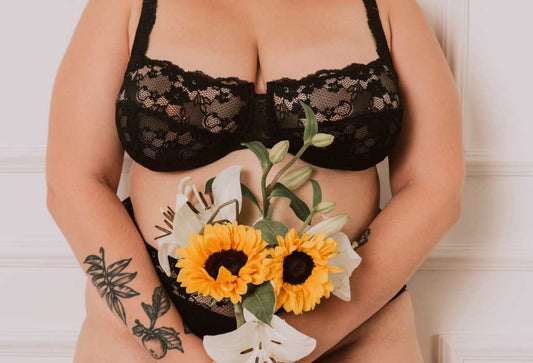 How many bra sizes are there: close up of a woman's chest wearing a lacey black bra and holding up a bouquet of sunflowers over her midriff