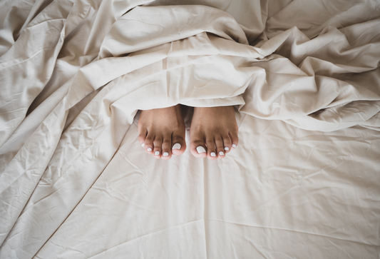 Products for more comfortable sex, feet peeking out from rumpled bed sheets