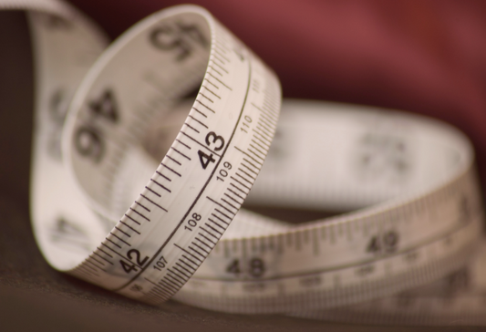 How bra size is measured, an image of a soft measuring tape coiled against fabric