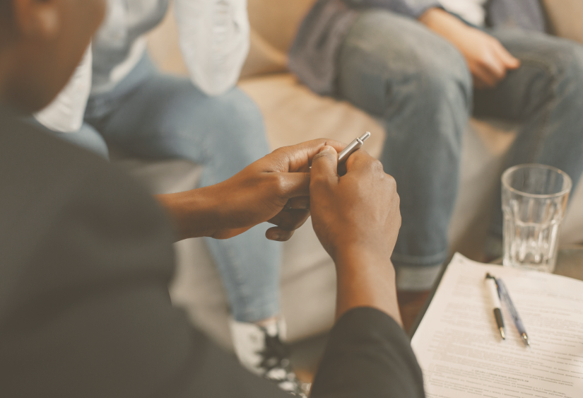 When should you go to couples therapy: a view of the therapist's hands as they face a couple sitting on a couch