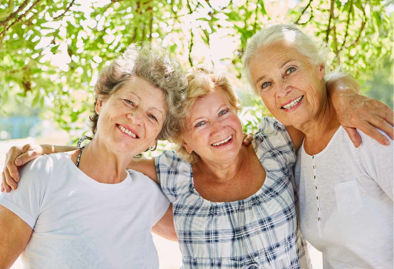 Why Comfortable Bras for Senior Women Make Aging Easier and Happier: Three senior women smiling and enjoying time together outdoors, representing comfort, confidence, and active aging supported by comfortable bras for seniors.