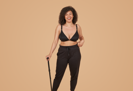 multiple sclerosis gifts: a young beautiful woman smiling joyfully at camera, leaning slightly on a walking stick while wearing the adaptive bra from Springrose