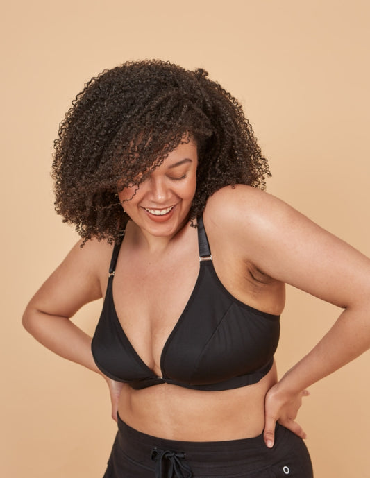 Young, busty woman smiling and looking down while wearing a comfortable, front opening adaptive bra