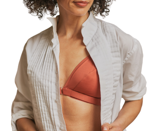 Mature woman with a half smile wearing the Springrose adaptive bra with velcro in terracotta under a white button down shirt