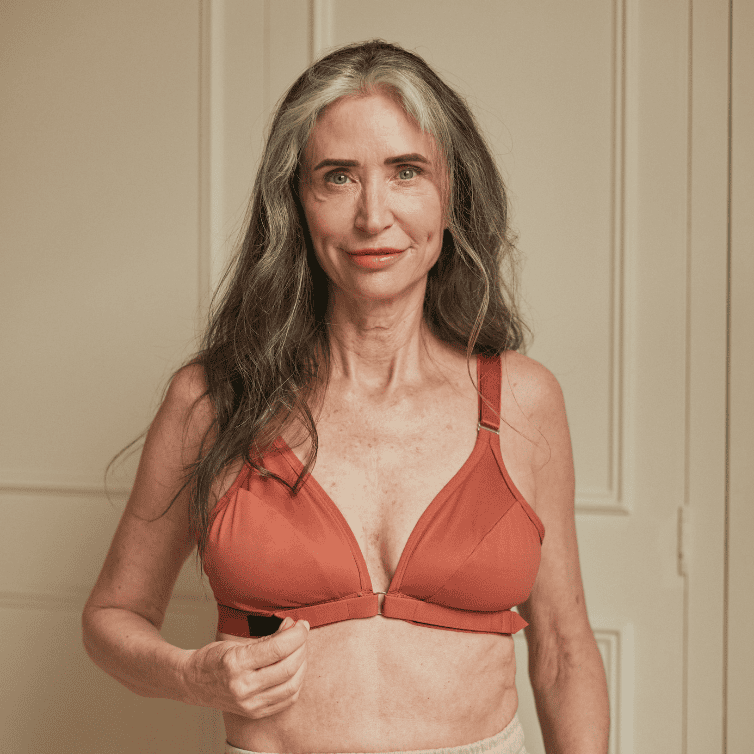 Older woman showing the arthritis bra with velcro front closure in terracotta.