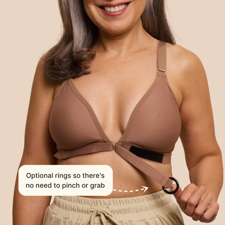 Close up of the easy-on mobility bra's optional gripping ring. The model is smiling and the adaptive bra is mocha colored. Text reads: optional rings so there's no need to pinch or grab.