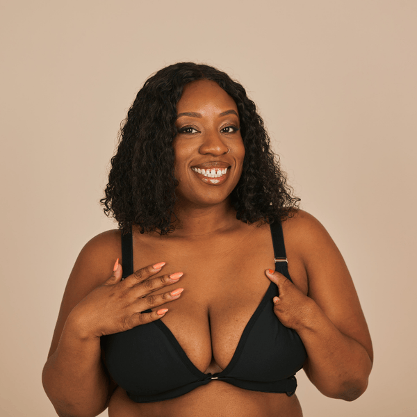 Beautiful model with a limb differences smiles widely at the camera while wearing the Springrose adaptive one handed bra in black.