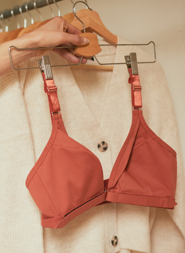 Woman grabbing the Springrose velcro front closure bra in terracotta from the closet