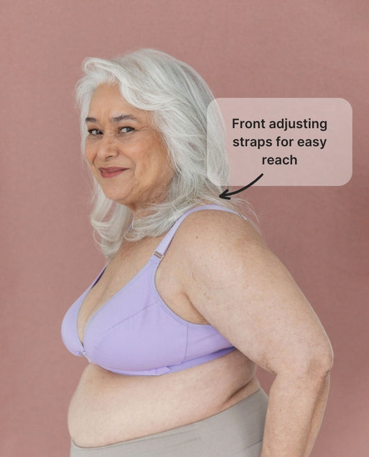 Beautiful model wearing the Springrose adaptive bra in lilac, showing off the bra's wide sides and smiling. Text reads: front adjusting straps for easy reach