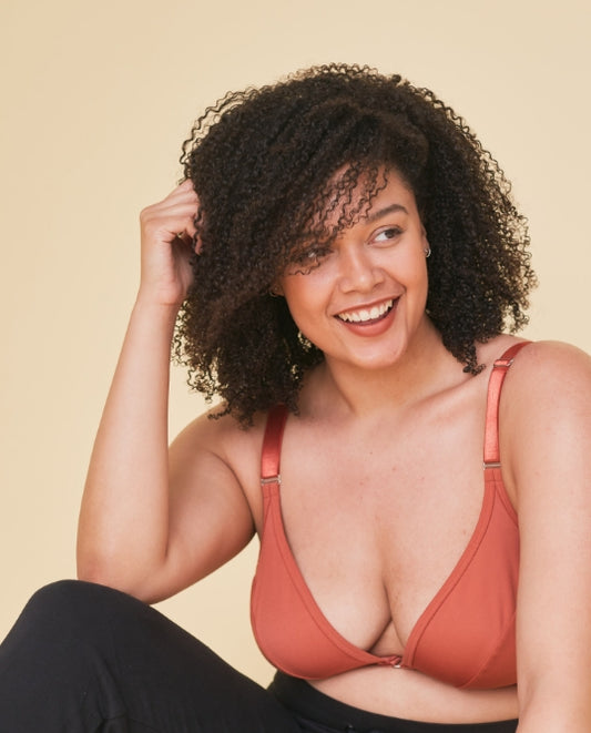 Happy, comfortable, and relaxed-looking woman who's smiling away from camera while wearing the front closing, adaptive velcro bra in terracotta