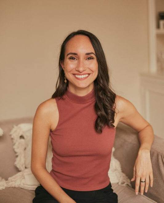 Nicole Cuervo, Springrose founder, sitting on a couch with a wide smile on her face