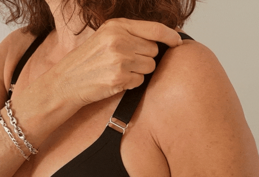 Close up of a woman adjusting the shoulder strap of the one handed adaptive bra