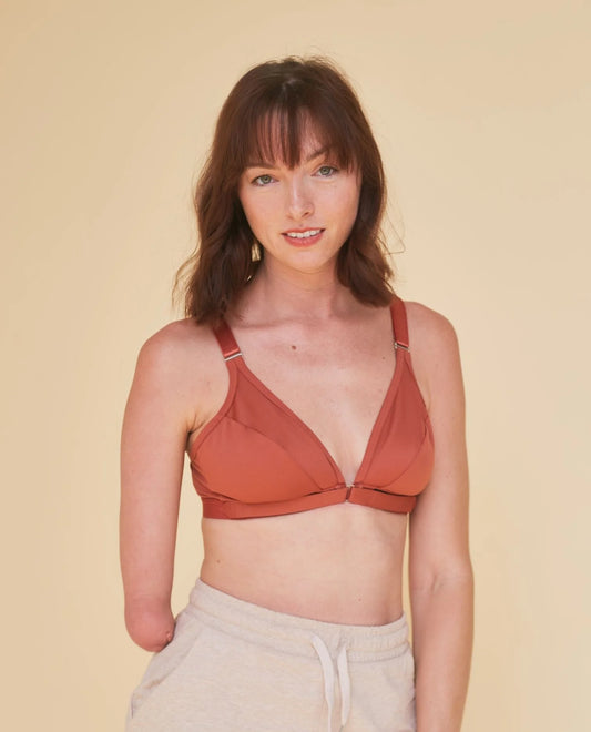 Beautiful young woman softly smiling at the camera while wearing the Springrose adaptive bra. She has a limb difference on her right side and is wearing the Springrose one handed bra.
